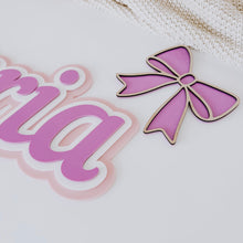Load image into Gallery viewer, Pink bow-shaped object next to a nameplate with 'Victoria' on a light background