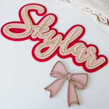 Load image into Gallery viewer, Decorative nameplate with 'Slylar' and a pink bow on a white background
